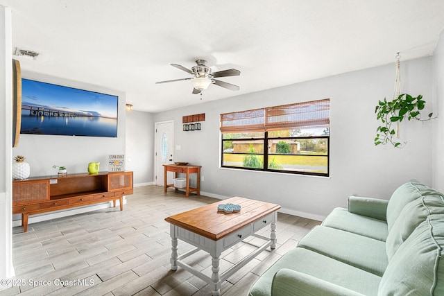 living area featuring a ceiling fan, light wood-type flooring, visible vents, and baseboards