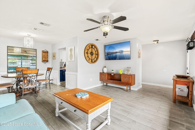 living room with wood tiled floor, visible vents, and a ceiling fan