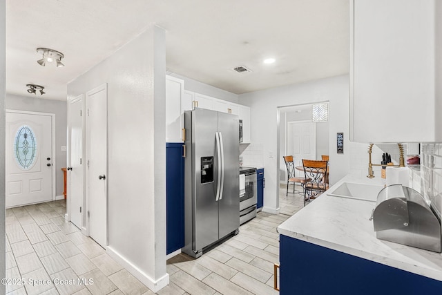 kitchen featuring a sink, visible vents, white cabinetry, appliances with stainless steel finishes, and backsplash