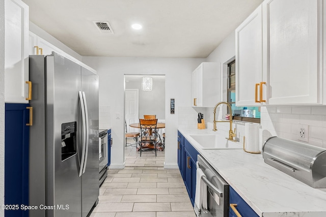 kitchen with blue cabinets, appliances with stainless steel finishes, white cabinets, and a sink