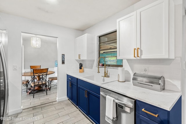 kitchen featuring blue cabinetry, tasteful backsplash, a sink, and dishwasher