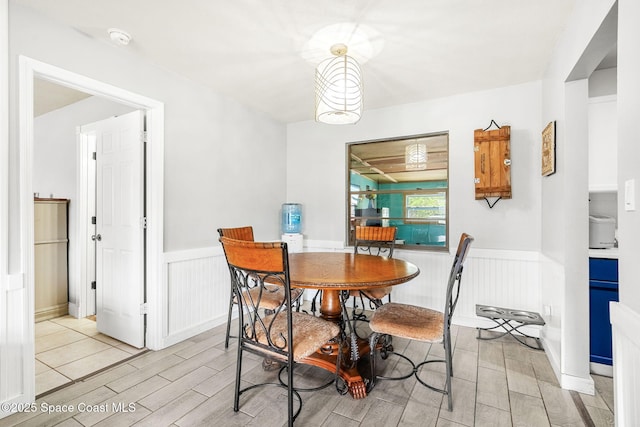 dining space with wood tiled floor and wainscoting