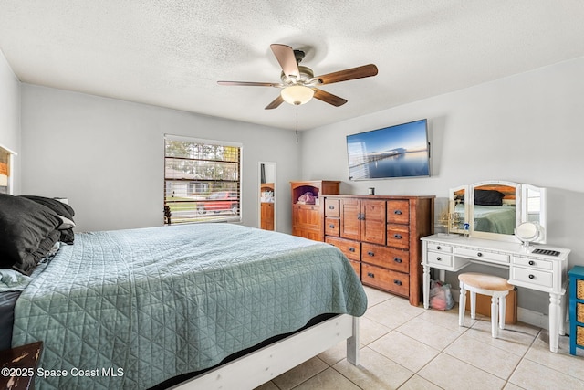 bedroom featuring a ceiling fan, light tile patterned flooring, and a textured ceiling