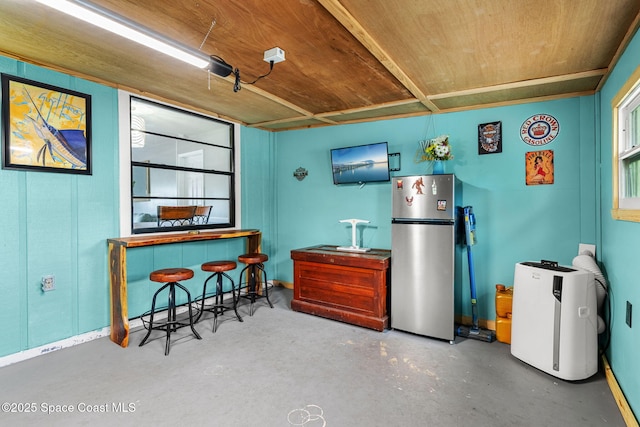 kitchen with wood ceiling, concrete floors, and freestanding refrigerator