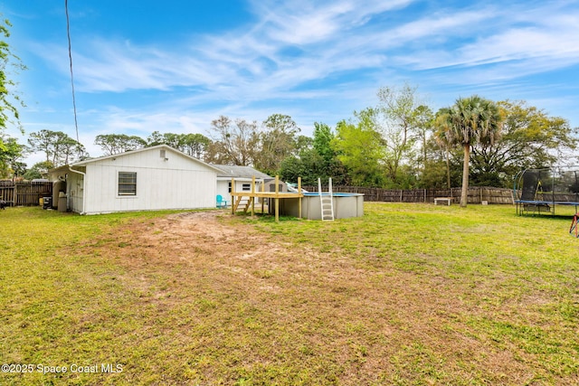 view of yard with a trampoline, a fenced in pool, and a fenced backyard