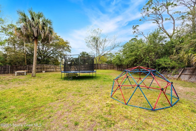 view of play area with a trampoline, a fenced backyard, and a lawn