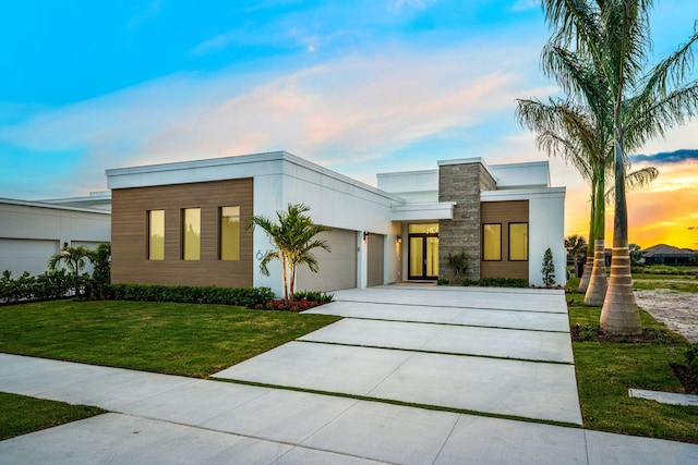 contemporary home featuring concrete driveway, a front lawn, and a garage