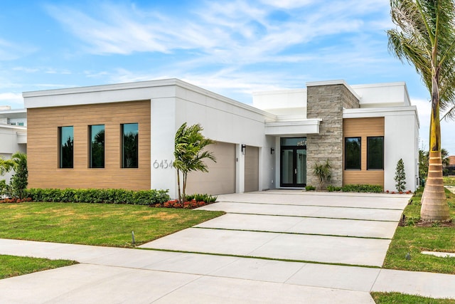 modern home with stucco siding, concrete driveway, a front lawn, a garage, and stone siding