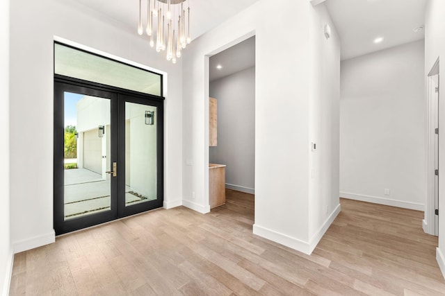 foyer entrance with french doors, baseboards, an inviting chandelier, and light wood-style flooring