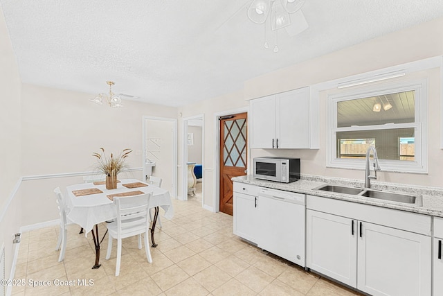 kitchen with a sink, ceiling fan with notable chandelier, a textured ceiling, white appliances, and white cabinets