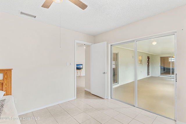 unfurnished bedroom featuring a textured ceiling, visible vents, a ceiling fan, and light tile patterned floors