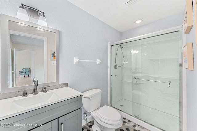 bathroom with vanity, toilet, a textured wall, a stall shower, and visible vents