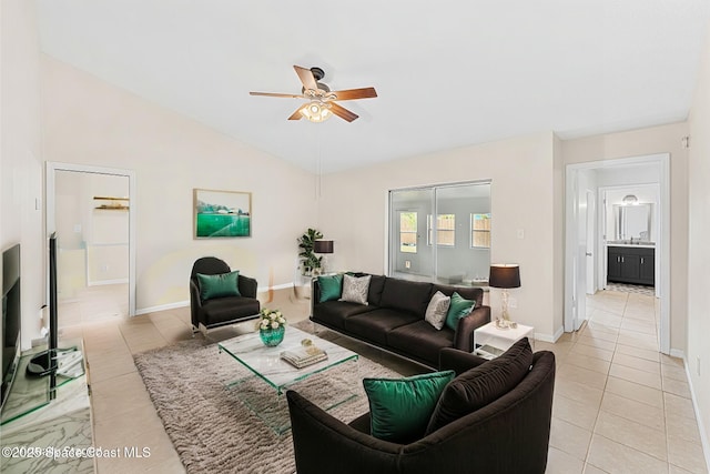 living area featuring baseboards, lofted ceiling, ceiling fan, and light tile patterned floors