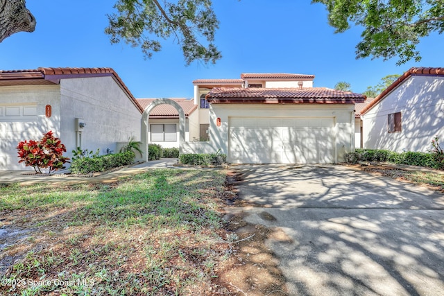 mediterranean / spanish home featuring stucco siding, a tiled roof, concrete driveway, and a garage