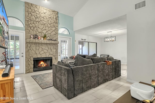 living area with baseboards, visible vents, an inviting chandelier, a fireplace, and a textured ceiling