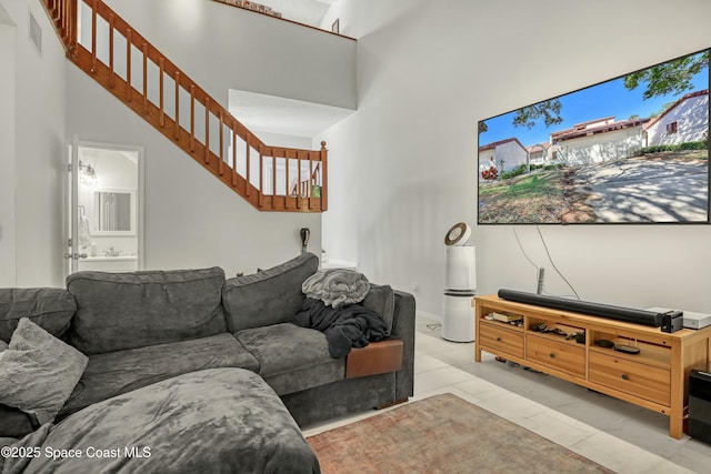 living room with light tile patterned floors, stairway, visible vents, and a towering ceiling