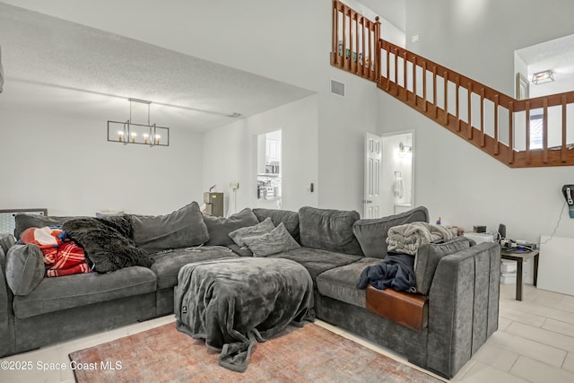 living area featuring visible vents, an inviting chandelier, light tile patterned flooring, stairs, and a textured ceiling