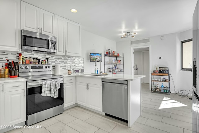 kitchen featuring a peninsula, stainless steel appliances, light countertops, and a sink