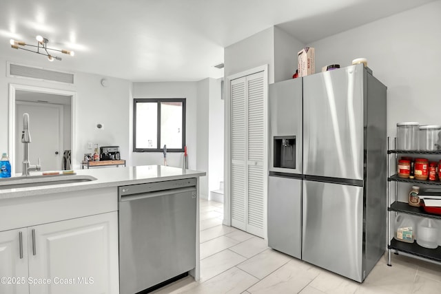 kitchen with visible vents, a sink, white cabinetry, stainless steel appliances, and light countertops