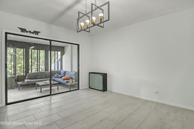 spare room with an inviting chandelier, baseboards, marble finish floor, and a textured ceiling