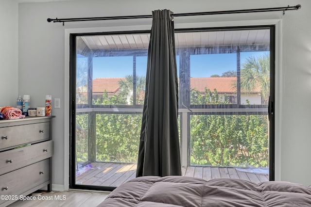 bedroom featuring access to exterior, multiple windows, and wood finished floors