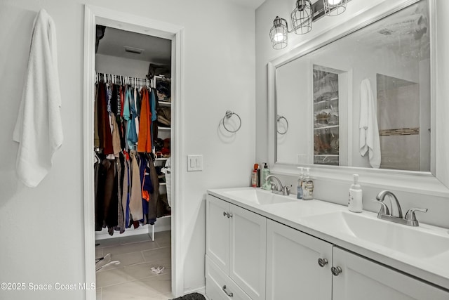 bathroom with double vanity, a spacious closet, visible vents, and a sink