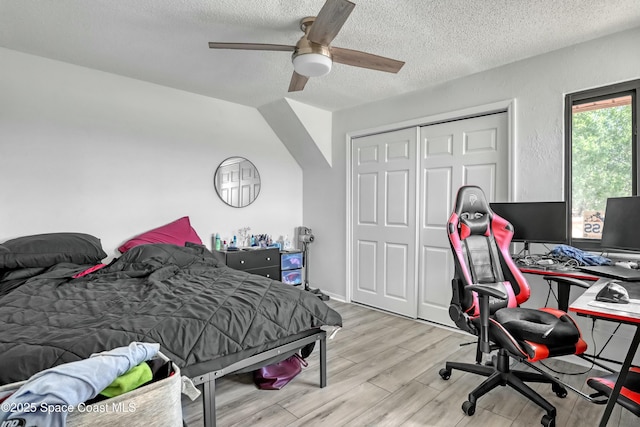 bedroom featuring a ceiling fan, wood finished floors, a closet, and a textured ceiling