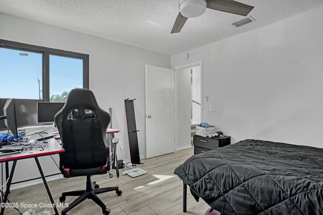 bedroom with visible vents, a textured ceiling, ceiling fan, and wood finished floors