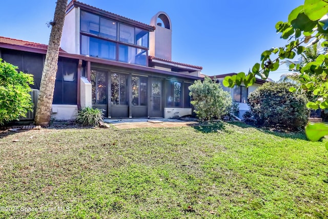 rear view of house featuring a lawn and a sunroom