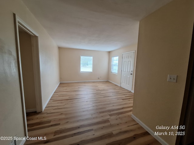 spare room with baseboards and wood finished floors