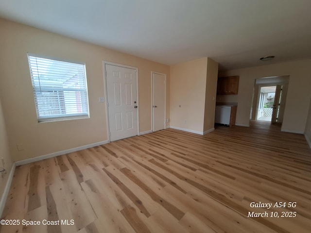 unfurnished living room with light wood-style flooring and baseboards