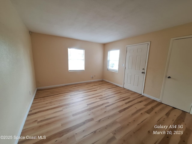 unfurnished room featuring light wood-type flooring and baseboards