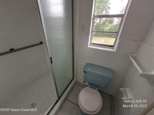 full bathroom featuring tile patterned flooring, tile walls, toilet, and a stall shower