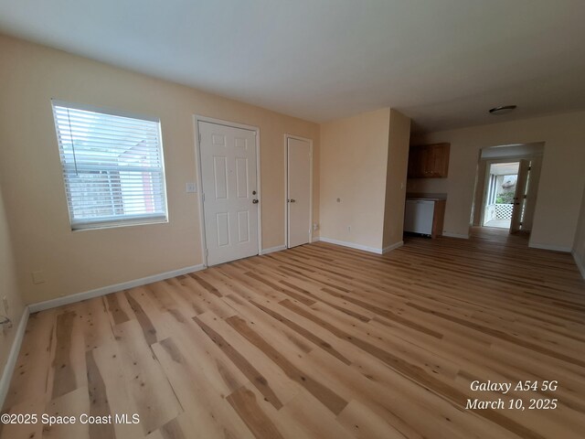 unfurnished living room featuring baseboards and light wood finished floors