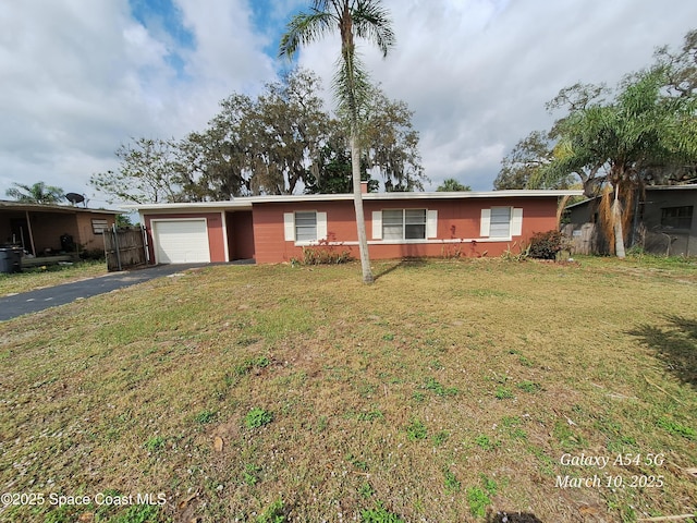 ranch-style home with a front lawn, an attached garage, fence, and driveway