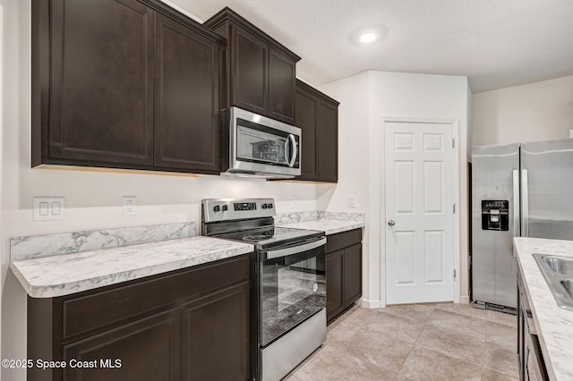 kitchen featuring dark brown cabinets, stainless steel appliances, and light countertops