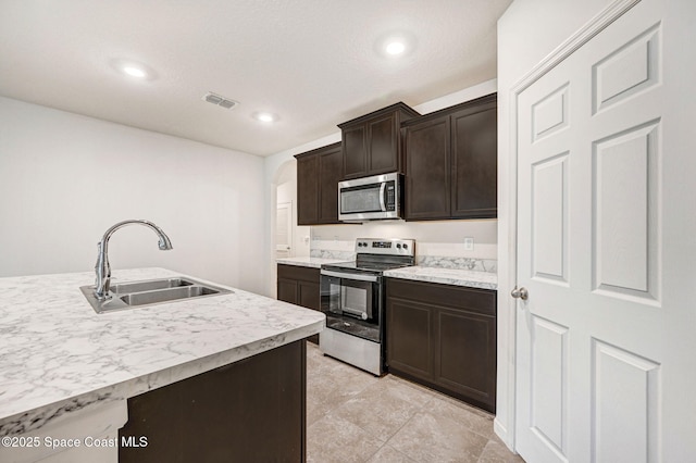 kitchen with visible vents, a sink, stainless steel appliances, light countertops, and dark brown cabinets