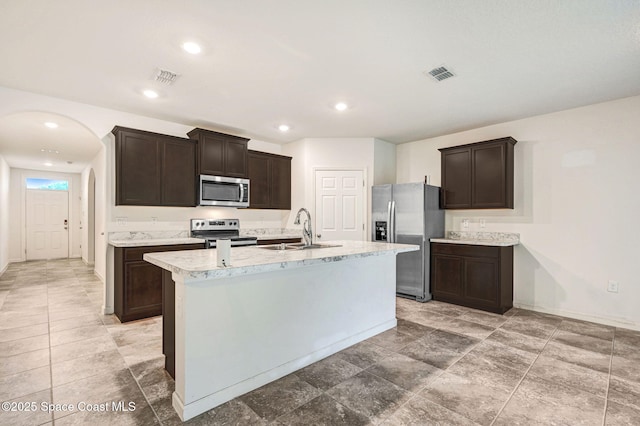 kitchen with visible vents, arched walkways, a sink, stainless steel appliances, and dark brown cabinets