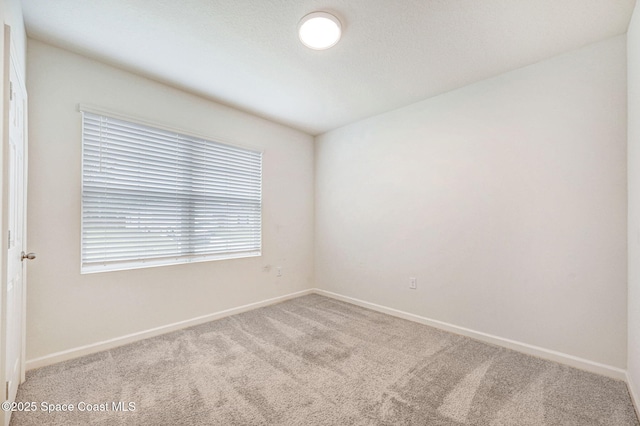 carpeted empty room featuring baseboards