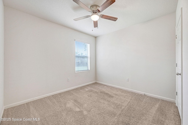 spare room featuring a ceiling fan, light colored carpet, baseboards, and a textured ceiling