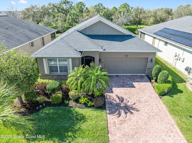 single story home featuring a garage, stone siding, decorative driveway, and stucco siding