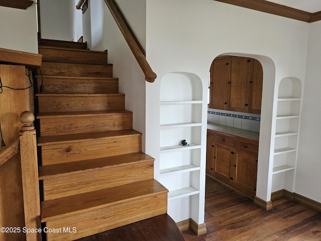 stairs featuring ornamental molding, wood finished floors, built in features, and baseboards