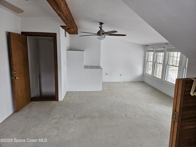 unfurnished living room with a ceiling fan, carpet flooring, and vaulted ceiling with beams