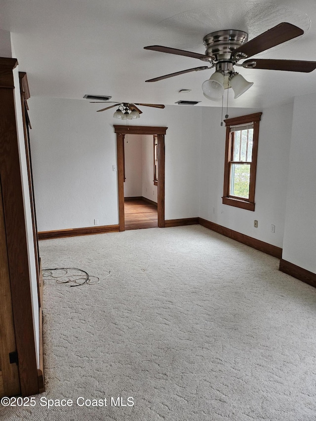 carpeted spare room with baseboards, visible vents, and a ceiling fan