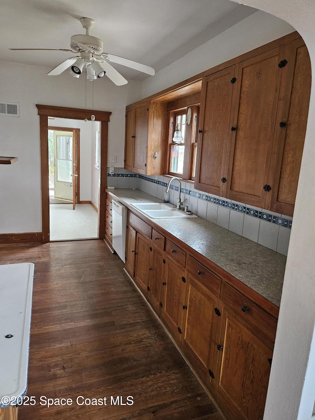 kitchen featuring brown cabinets, visible vents, white dishwasher, and a sink