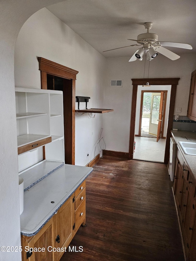 kitchen with white dishwasher, a sink, visible vents, baseboards, and dark wood finished floors