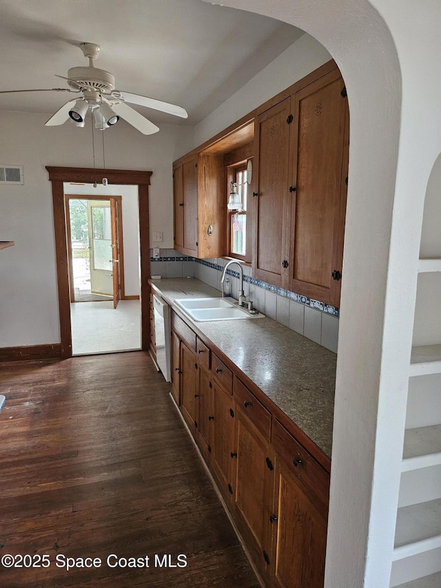 kitchen with white dishwasher, visible vents, brown cabinets, and a sink