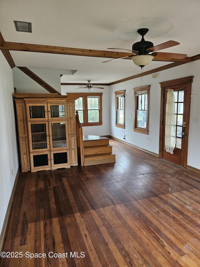 unfurnished living room featuring dark wood finished floors, visible vents, ceiling fan, beamed ceiling, and baseboards