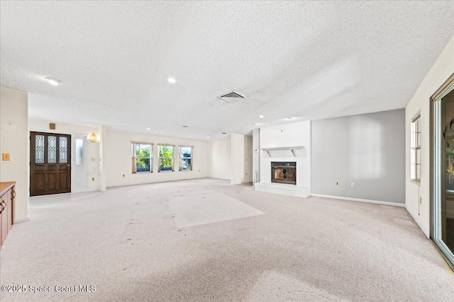 unfurnished living room with baseboards, visible vents, a fireplace, a textured ceiling, and light carpet