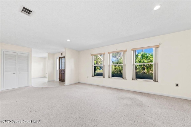 spare room with visible vents, plenty of natural light, and light colored carpet